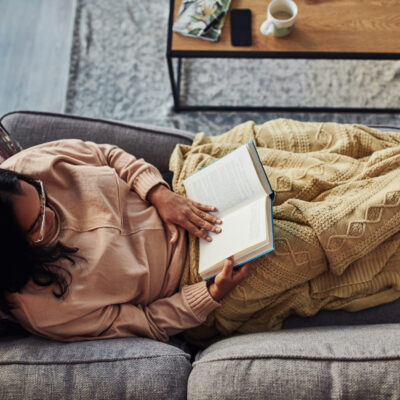Woman practicing self care by reading a book on the couch