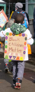 Black Child marching with sign on their back: Black Children Matter